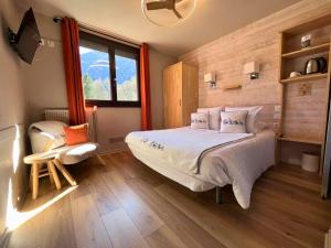 a bedroom with a bed and a chair and a window at Hôtel La Rencluse in Luchon