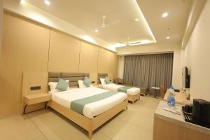 a hotel room with two beds and a television at Sarju Palace in Valsād