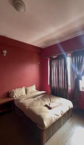 a bed in a room with a red wall at Konjyosom Homestay-Experience Real Nepali Hospitality in Kathmandu