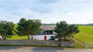 a house in a field with trees and a fence at Bath Cottage in Caernarfon