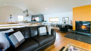a living room with a leather couch and a kitchen at Bath Cottage in Caernarfon