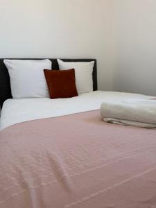 a bed with white pillows and a pink blanket at Le Verger in Alixan