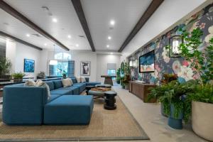 a large living room with blue couches and plants at The Village Collection with Gym Pool and Spa in Montclair