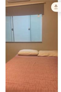 a bed with two pillows in a room with a window at Casa Baviera -MOTO GP GOIANIA in Aparecida de Goiânia