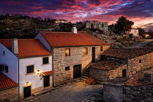 a group of stone buildings with a sunset in the background at Casa do Miradouro in Guarda