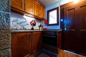 a kitchen with wooden cabinets and a black dishwasher at Casa do Miradouro in Guarda
