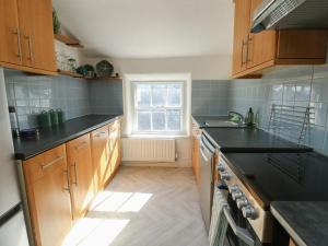 a kitchen with wooden cabinets and black counter tops at Castle Gardens Apartment in Beaumaris