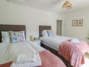 a bedroom with two beds with pink and white sheets at Castle Gardens Apartment in Beaumaris