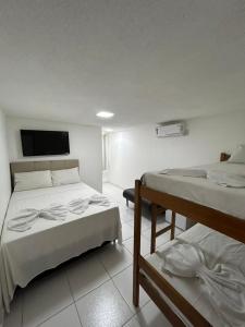 a room with two beds and a flat screen tv at Pousada Avenida MELHOR CUSTO-BENEFÍCIO in Teixeira de Freitas