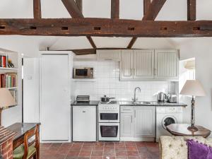 a kitchen with white appliances and a brick floor at Old Rectory Cottage in Fernhurst