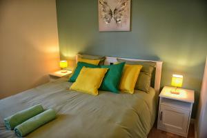 a bedroom with a bed with green and yellow pillows at Fleur des Vents in Saint-Flour