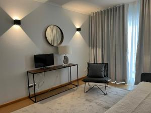 a bedroom with a bed and a chair and a mirror at Hotel do Mar in Povoação