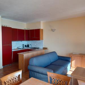 a living room with a blue couch and a kitchen at Residence Il Vigneto - Casa Sopralago in Oggebbio