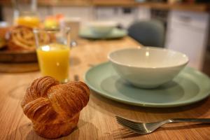 a table with a plate of bread and a bowl of orange juice at Fleur des Vents in Saint-Flour
