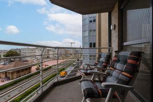 a balcony with chairs on a building with a train track at Casiola - Spacious apartment with private car park in Blankenberge