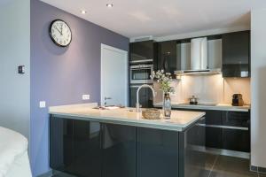 a kitchen with a sink and a clock on the wall at Casiola - Spacious apartment with private car park in Blankenberge