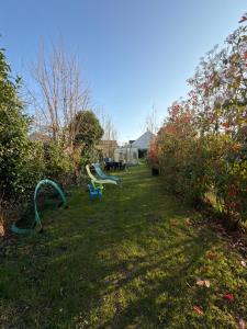 a yard with two green benches in the grass at Homewood - entire property for 6 people - 4 adults maximum - in village 10 min from Disneyland Paris & TGV RER A in Montry