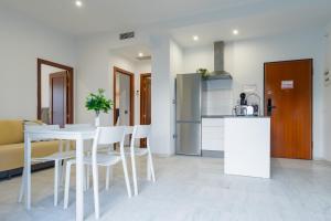 a kitchen and dining room with a table and chairs at Áticos Lux Sevilla Piscina Parking in Bormujos