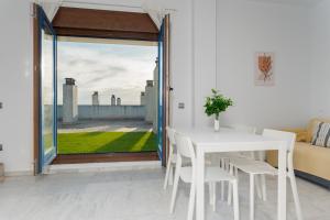 a white table and chairs in a room with a window at Áticos Lux Sevilla Piscina Parking in Bormujos