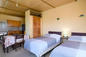 a bedroom with two beds and a table and a kitchen at Esaw Place in Christ Church