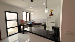 a kitchen with a black counter and a refrigerator at Casa moderna, amplia y acogedora Valentina in Loja