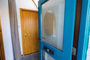 a blue door with a window next to a wooden door at Sound House, Shetland Islands in Lerwick