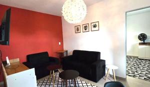 a living room with two black chairs and a red wall at Apartamento Estilo Moderno in Belo Horizonte