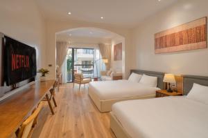 a hotel room with two beds and a desk with a television at Home en Lagom in Hanoi