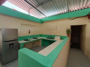 a green and white kitchen with a sink and a refrigerator at Turquesa Bacalar Centro in Bacalar