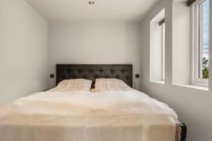 a bed in a white room with two windows at Trolltunga Fjords in Tokheim