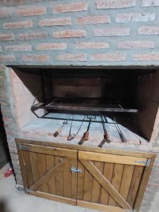 a brick fireplace with a wooden cabinet with a grill at Cabaña la Gabita in Villa Ciudad Parque