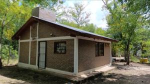 a small brown brick house with trees in the background at Cabaña la Gabita in Villa Ciudad Parque
