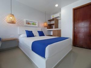 a bedroom with a large white bed with blue pillows at Hotel Portoalegre in Coveñas