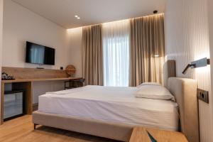 a bedroom with a large bed and a television at Kamara Rooms in Sarandë