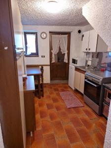 a kitchen with white cabinets and a wooden floor at maso denis in Canale San Bovo
