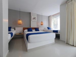 a white bedroom with two beds and a window at Hotel Portoalegre in Coveñas +33 photos