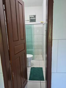 a bathroom with a toilet and a green rug at Silsol in Itacaré