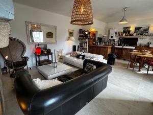 a living room with a black leather couch and a table at Charming house in an old rectory PMR in Tréguier