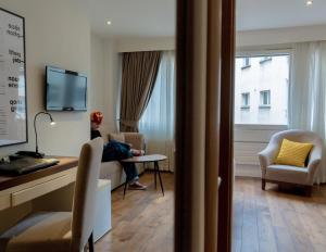 a room with a desk and a person sitting in a chair at Hotel Alpha in Fribourg