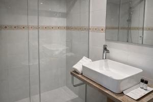 a white bathroom with a sink and a shower at Aparthotel Montcada in Montcada i Reixac