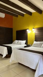 a room with two beds and a yellow wall at Hotel El Rancho in San Juan Bautista Tuxtepec
