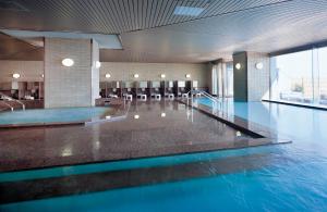 a swimming pool with blue water in a building at Hotel Ambia Shofukaku in Yaizu