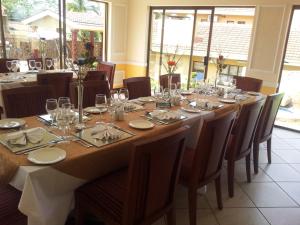 a long table in a restaurant with chairs and glasses at Open House Boutique in Manzini