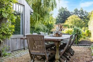 a wooden table in a garden with chairs around it at Casiola - Authentic vacation home 'De Blauwe Kroon' in Oostkamp