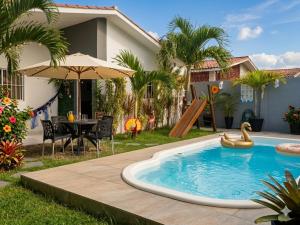 a pool in a backyard with a table and an umbrella at Garden JP in João Pessoa