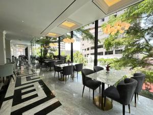 a restaurant with tables and chairs and windows at Grand Eska Hotel & Suites Batam in Nagoya