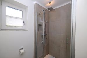a bathroom with a shower with a glass door at Friesenjung in Wenningstedt +14 photos