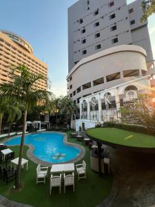 a building with a pool and tables and chairs at Grand Eska Hotel & Suites Batam in Nagoya +99 photos