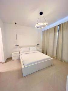a white bedroom with a white bed and two lights at Downtown Chic Donde inicia la diversión en Punta Cana in Punta Cana +45 photos