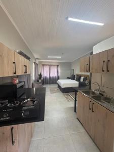 a room with a kitchen and a bed in the background at Green Haven Waitara in Tzaneen +9 photos